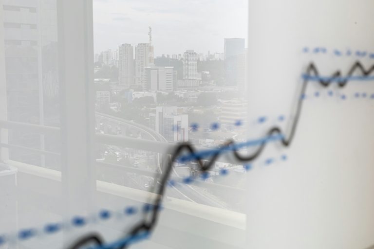 een stijgende groeicurve op een whiteboard. In de reflectie is de skyline van een stad zichtbaar. 